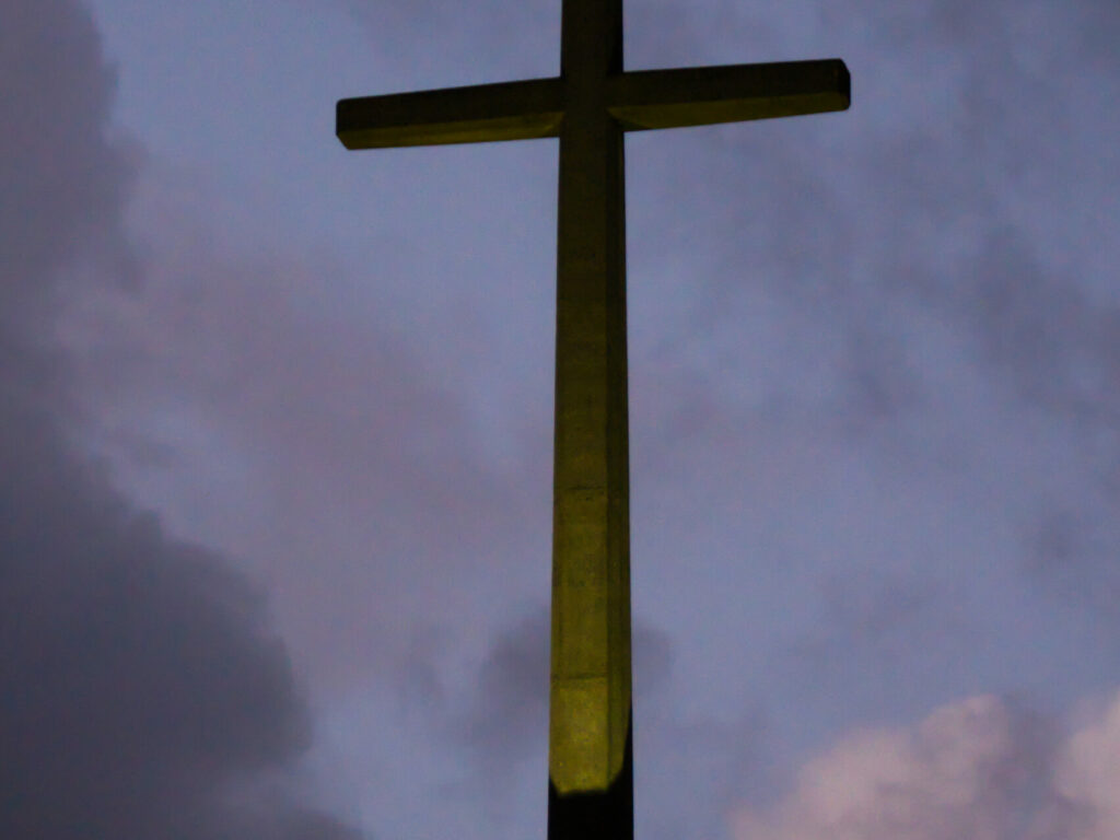 A cruz iluminada ao lado da Ermida de Nossa Senhora da Paz na escuridão após o pôr-do-sol A cruz iluminada ao lado da Ermida de Nossa Senhora da Paz na escuridão após o pôr-do-sol